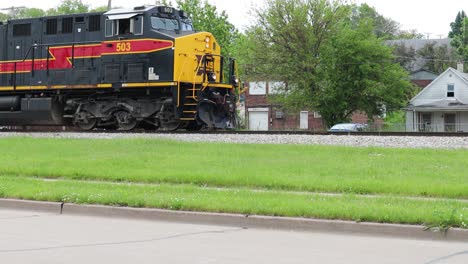 Motor-De-Ferrocarril-Interestatal-De-Iowa-Empujando-Lentamente-El-Tren-Por-La-Vía-Más-Allá-Del-Tráfico-Y-Las-Casas
