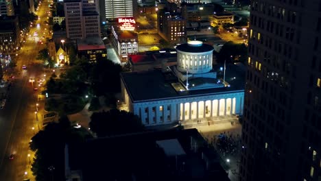 Aerial-view-of-the-Ohio-Statehouse-and-traffic-in-lit-up-Columbus-city---reverse,-drone-shot
