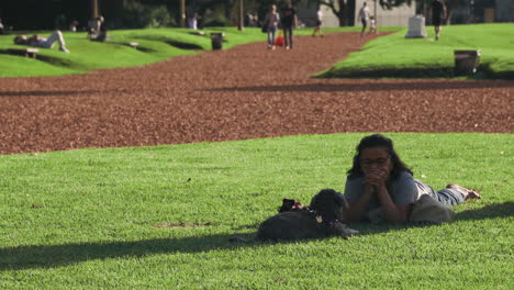 Woman-with-her-dog-lying-on-park-lawn