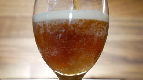 Pouring-fresh-and-tasty-dark-beer-into-glass,-close-up-view
