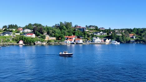 Ein-Kleines-Targa-Vergnügungsboot,-Das-An-Einem-Strahlend-Sonnigen-Tag-Durch-Die-Bucht-Von-Hjellestad-Segelt-–-Statische-Aufnahme-Von-Norwegen-Mit-Teuren-Häusern-Im-Hintergrund