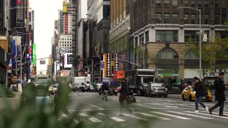 Pedestrian-walking-on-the-street-with-traffic-car-and-yellow-cab-in-a-touristic-main-road-of-New-York-City