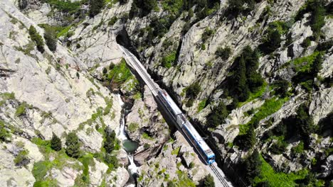 Aerial:-rack-railway-running-along-a-green-valley-in-spring-time-and-entering-a-tunnel