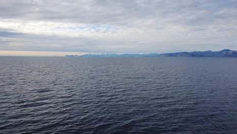 View-from-a-ferry,-mountain-chains-of-the-Lofoten-island-far-away