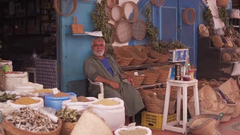 An-old-man-in-the-marchandise-of-Djerba-houmet-souk-selling-accessories-and-decorations-in-front-of-his-store