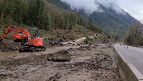 Construction-digger-bulldozer-and-essential-vehicles-working-on-closed-mountain-highway-route