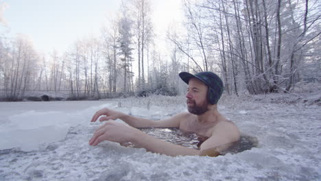 An-ice-bather-enters-the-ice-hole-and-sits-down-up-to-his-neck,-breathing