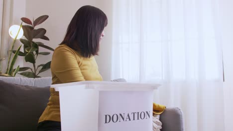 Mujer-Seleccionando-Ropa-Para-Donar-Y-Poner-En-Caja