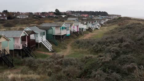 Dolly-forwards-drone-shot-towards-colourful-beach-huts-english-seaside