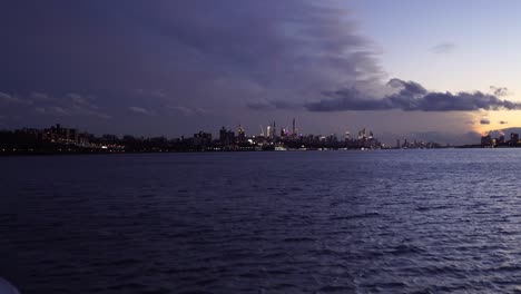 Amazing-cityscape-of-modern-metropolitan-skyline,-boat-approach-New-York-City-center-during-an-epic-cloudy-sunset
