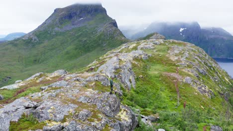Excursionista-Masculino-De-Pie-En-Un-Terreno-Rocoso-Cerca-Del-Pico-De-La-Montaña-Segla-En-La-Isla-Senja,-Noruega