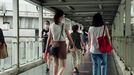 People-wearing-masks-walk-on-a-bridge-connecting-the-central-mass-transit-system-during-the-COVID-19-pandemic