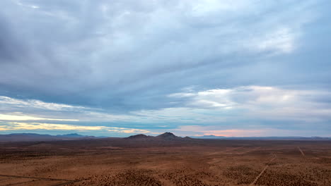 Mojave-Desert-basin-and-landscape-with-the-mountains-in-the-distance-and-a-cloudscape-overhead---panoramic-aerial-hyper-lapse