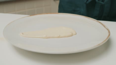 Placing-homemade-mayonnaise-onto-big-plate-on-kitchen-table