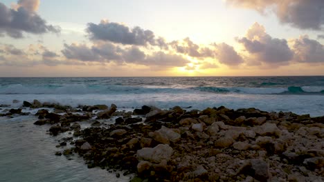 View-at-sunset-from-drone-as-waves-crash-on-tropical-beach-in-Tulum,-Mexico