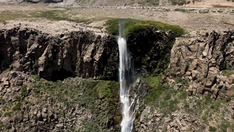 Aerial-view-of-a-crane-shot-of-the-inverted-waterfall-with-a-rainbow-appearing-all-along-its-path-on-a-sunny-day-in-Maule,-Chile