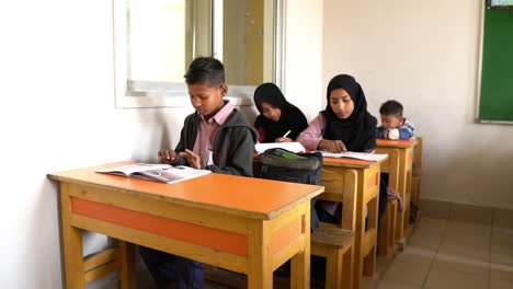 Junge-Muslimische-Schulkinder-Lernen-Am-Schreibtisch-Im-Klassenzimmer-In-Karatschi,-Pakistan