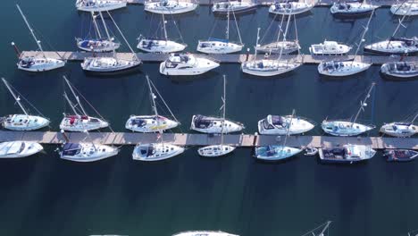 A-forward-flying-drone-shot-of-above-and-over-many-marina-pontoons-with-sailing-yachts-and-motorboats-tied-to-them
