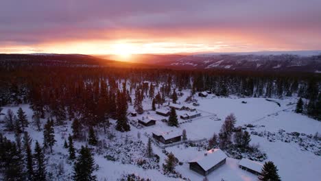 Brennender-Sonnenuntergang-über-Der-Winterlichen-Bergwaldlandschaft-Mit-Holzhütten