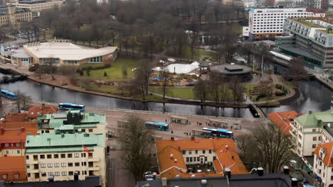 Public-bus-stop-on-downtown-of-majestic-town-Borås-with-colorful-buildings,-aerial-drone-view