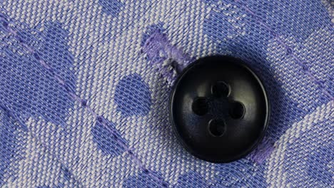 Black-Plastic-Sew-Button-Attach-On-Blue-Woven-Patterned-Fabric