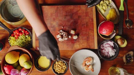 Straight-down-view-of-a-professional-chef-cutting-and-slicing-octopus-tentacle,-scallops-and-prawns-into-small-pieces-on-a-chopping-board,-preparing-for-authentic-ceviche-seafood-salad-starter