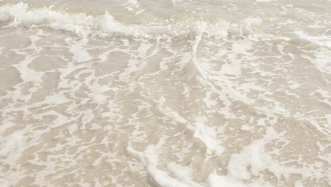 Close-up-of-waves-rolling-onto-tropical-sand-beach-in-slow-motion