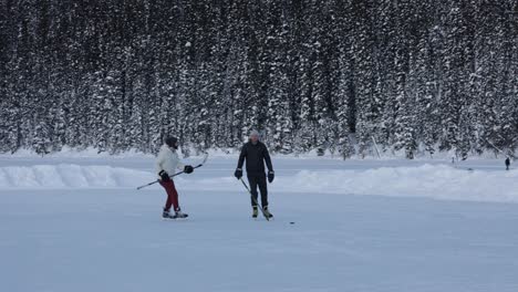 Männer-Spielen-Eishockey-Auf-Dem-Zugefrorenen-Lake-Louise-Mit-Wald-Als-Hintergrund,-Winterlandschaft