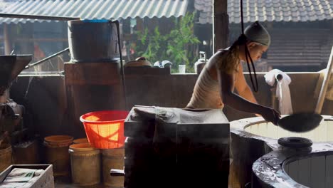 Worker-at-traditional-tofu-factory-pours-dough-into-press-in-Indonesia