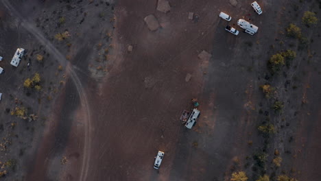 Aerial-top-down-view-of-RVs-parked-in-an-Arizona-desert,-tilting-up-the-sun