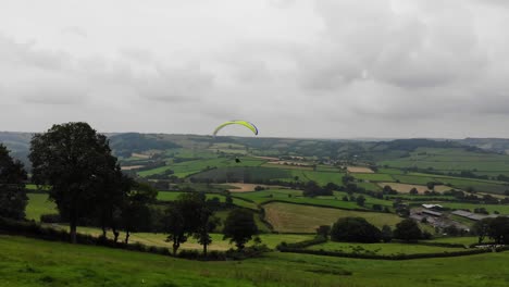 Forward-shot-following-a-Paraglider-soring-into-the-sky-over-the-English-Countryside