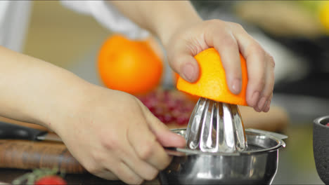 Close-up-of-young-woman-cutting-and-juicing-orange