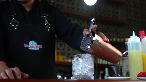 Latin-Mexican-Bartender-serving-strawberry-cocktail-from-shaker-in-slow-motion
