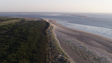 Aerial-flight-along-tidal-ocean-currents-on-Oostvoorne-bay-and-lush-dune-forest