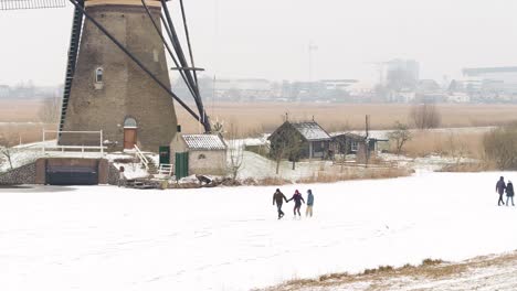 Historical-landmark-of-Kinderdijk-with-people-ice-skating-next-to-windmills