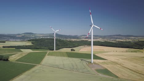 Aerial-dolly-in-of-windmills-turbines-in-farm-fields-at-daytime-generating-clean-renewable-energy-for-sustainable-development