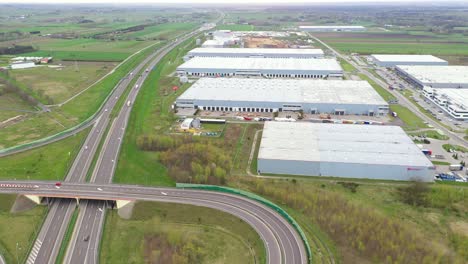 Aerial-Shot-of-Industrial-Warehouse-Storage-Building-Loading-Area-where-Many-Trucks-Are-Loading-Unloading-Merchandise