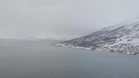 Snow-covered-coastline-in-arctic-along-foggy-Kaafiord,-Olderdalen