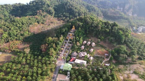 Drone-Aéreo-De-Un-Templo-único-Con-Un-Buda-Dorado-En-Una-Montaña-Rodeada-De-Cocoteros-En-Ao-Nang-Krabi-Tailandia