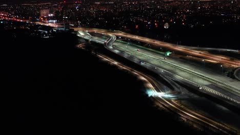 Aerial-flyover-traffic-jam-interchange-road-at-night,-drone-shot-top-down-view-roadway-intersection-in-modern-city-in-evening