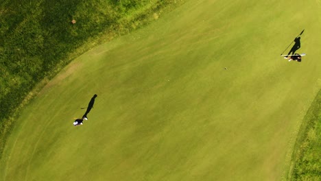 Aerial-top-down-over-golfer-hits-ball-rolling-towards-hole-on-putting-green