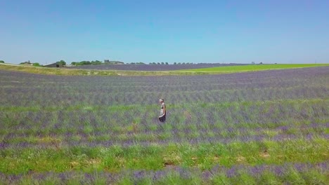Young-woman-walking-through-rows-of-beautiful-lavender-in-the-stunning-countryside-of-Provence,-France
