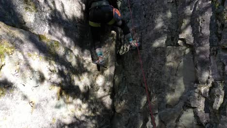 Woman-Climbing-On-Steep-Rock-Face-In-Whitefish,-Montana-USA---tilt-up-shot