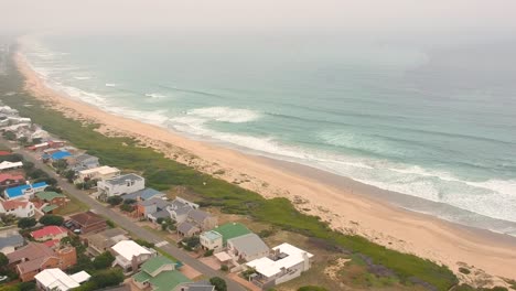 Misty-drone-view-of-travel-beach-town-and-ocean-waves
