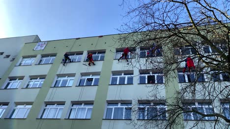 Charity-Climbers-for-WOSP-clean-windows-in-children's-hospital-in-funny-outfit-on-Polanki-Street-in-Gdansk,-Maciej-Płażyński-Hospital,-mountaineers-work-socially