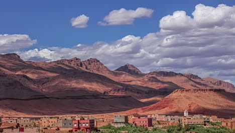 Time-lapse-shot-of-flying-clouds-over-village-in-Morocco-and-red-mountains-in-background