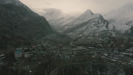 Große,-Rotierende-Aufnahme-Von-Häusern,-Die-Sich-über-Dem-Berg-Aufbauen,-Mit-Einem-Schneebedeckten-Berg-Im-Hintergrund
