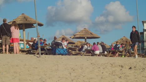 People-Eating-and-Drinking-Enjoying-the-Summer-at-The-Watering-Hole-Beach-Bar-Restaurant,-Perranporth,-Cornwall