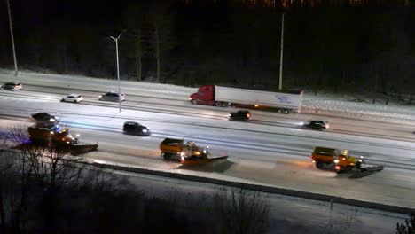 Lined-up-snowplows-removing-the-snow-on-the-highway-on-a-cold-snowy-winter-night