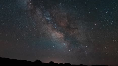 Tracking-the-Milky-Way-in-brilliant-color-as-it-crosses-the-sky-above-the-desert-horizon---time-lapse